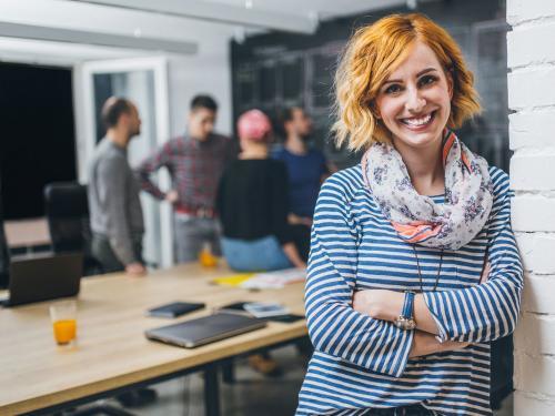 Photo of young business woman in a conference room, with a group of coworkers in backside