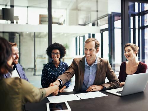 Shot of colleagues shaking hands during a meeting at work