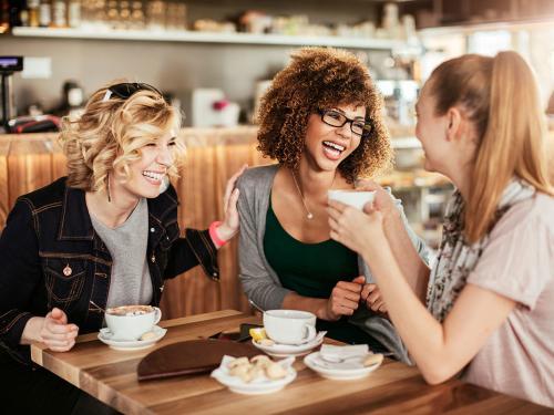 Close up of best friends using a mobile phone while at a cafe